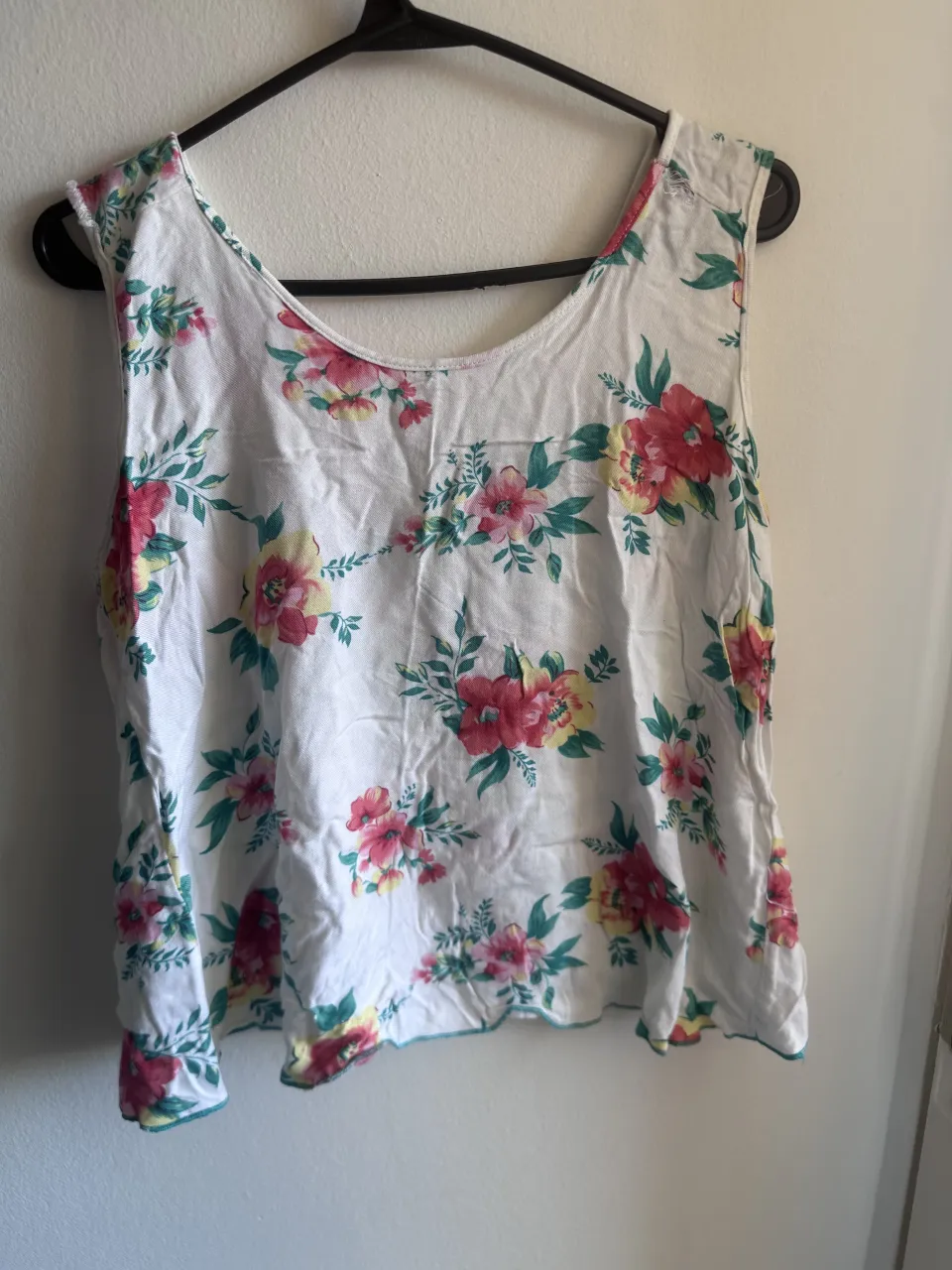 Musculosa blanca con estampa floral de flores rojas, rosas y amarillas con hojas verdes. Posee un cruce en la parte delantera.