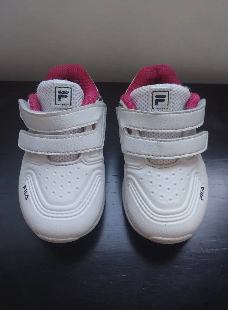 Zapatillas deportivas blancas para bebé con detalles en fucsia y abrojo.