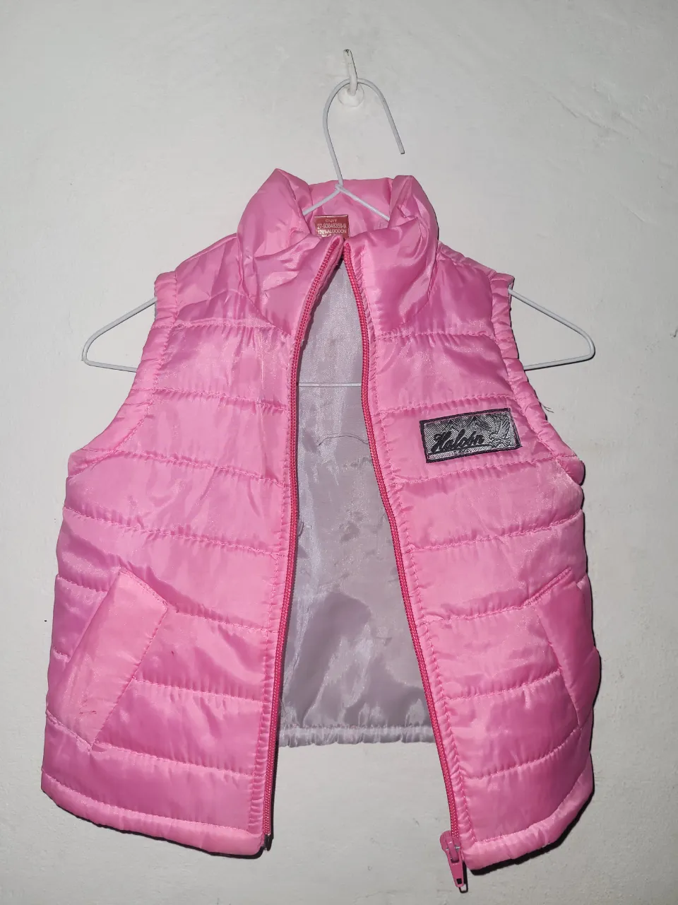 Chaleco acolchado rosa con cierre al frente y bolsillos laterales.