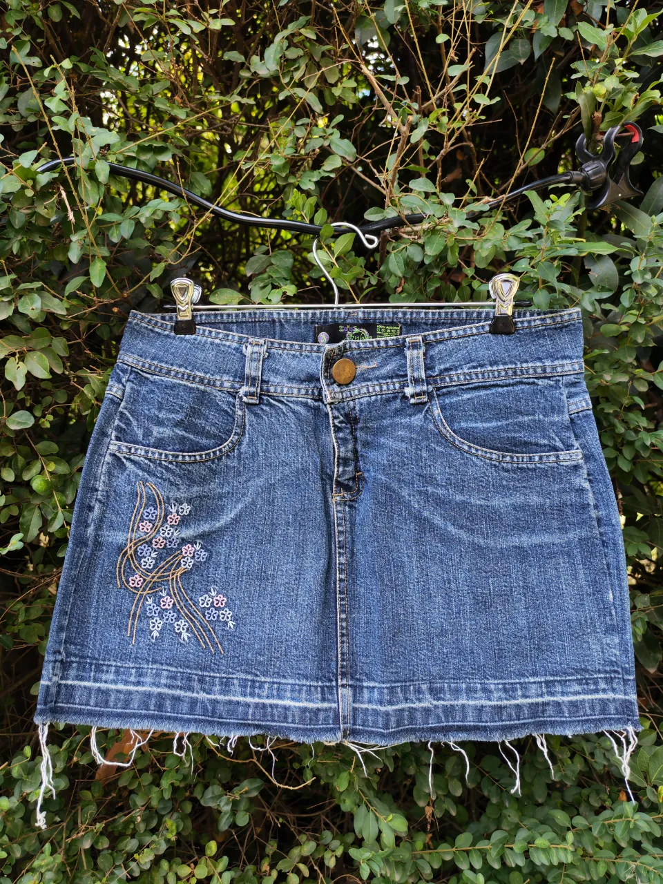 Pollera de jean con bordado floral en la parte delantera y detalles desflecados en el ruedo. Un clásico que no puede faltar en tu guardarropa.