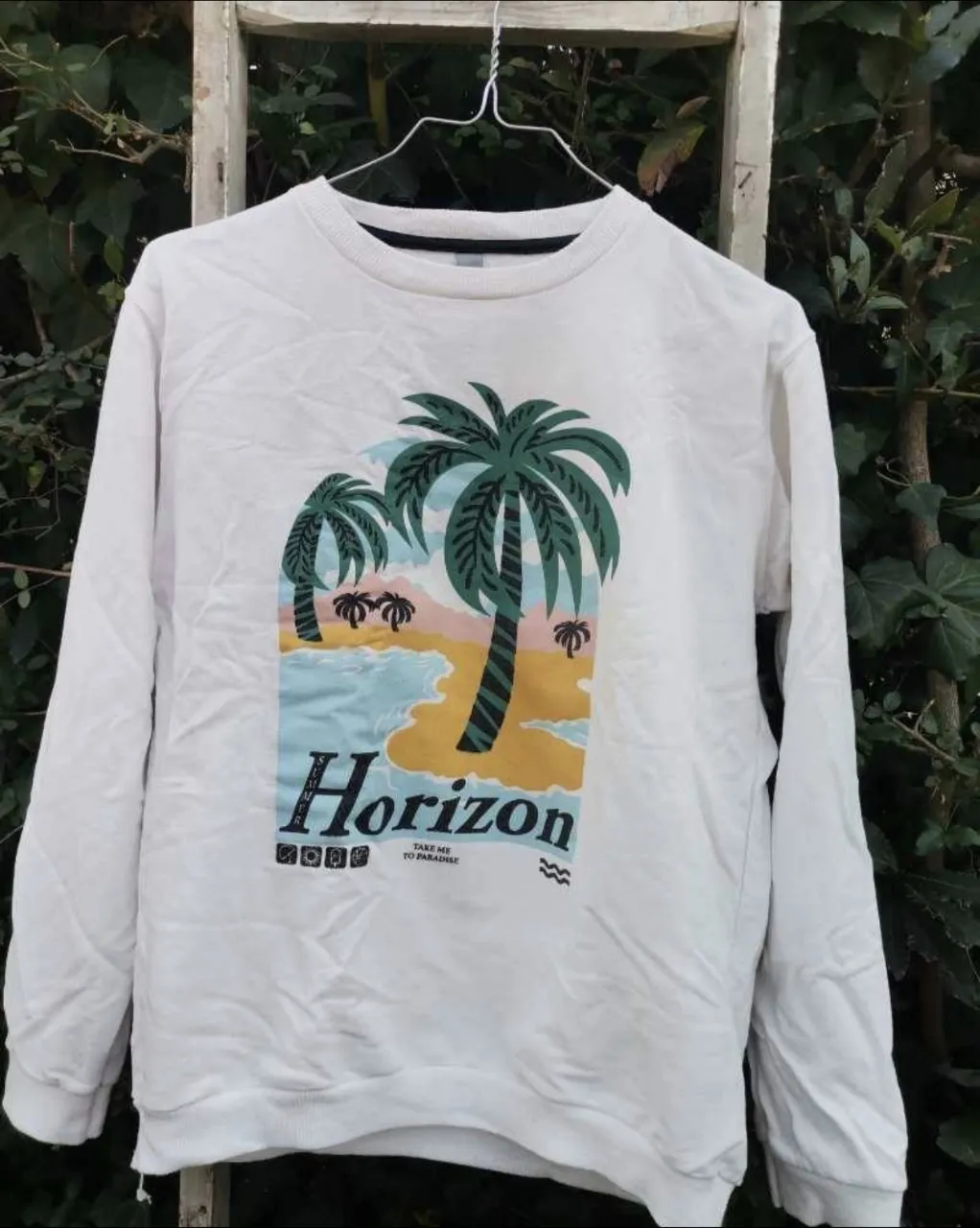 Buzo blanco con estampa de palmeras y la palabra "Horizon".