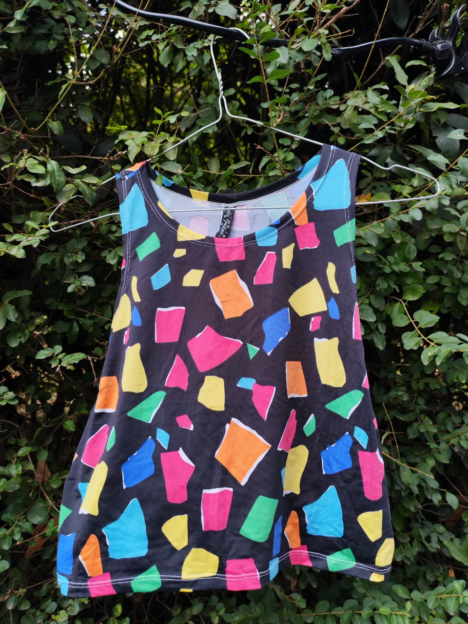 Top con estampa abstracta multicolor sobre fondo negro.