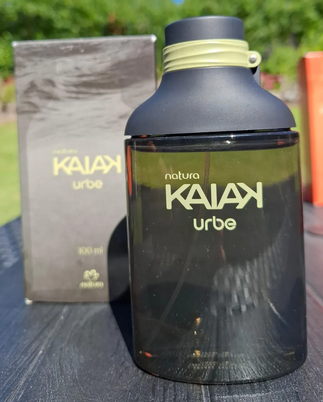 Perfume Kaiak Urbe de Natura. Envase de vidrio oscuro con tapa negra y detalle verde. Incluye caja.