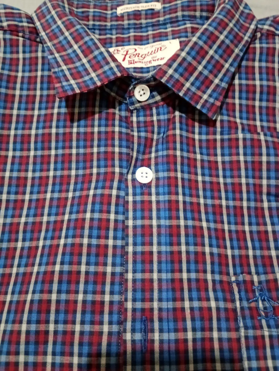 Camisa a cuadros de manga larga con botones blancos y bolsillo en el pecho.