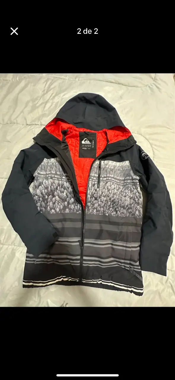 Campera de ski Quiksilver, con capucha, cierre frontal y diseño estampado. Ideal para la nieve y el invierno.
