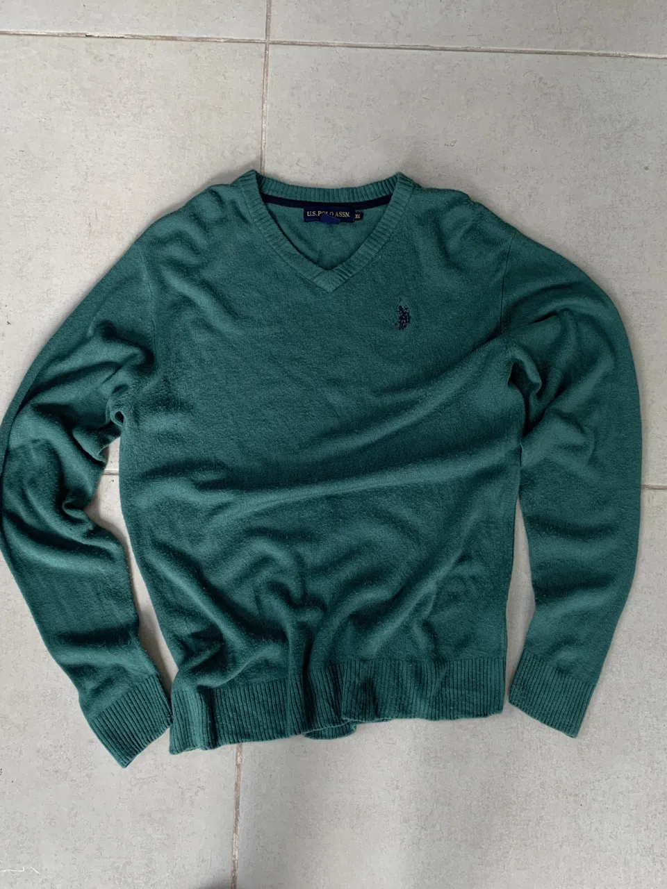 Sweater de lana de manga larga, cuello en V y logo bordado en el pecho. Ideal para un look casual y cómodo.