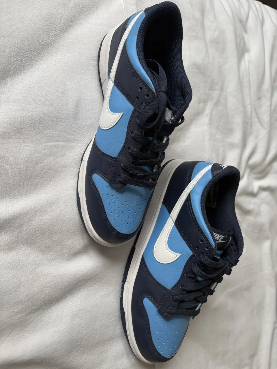 Zapatillas deportivas Nike color azul marino y celeste con detalles blancos.