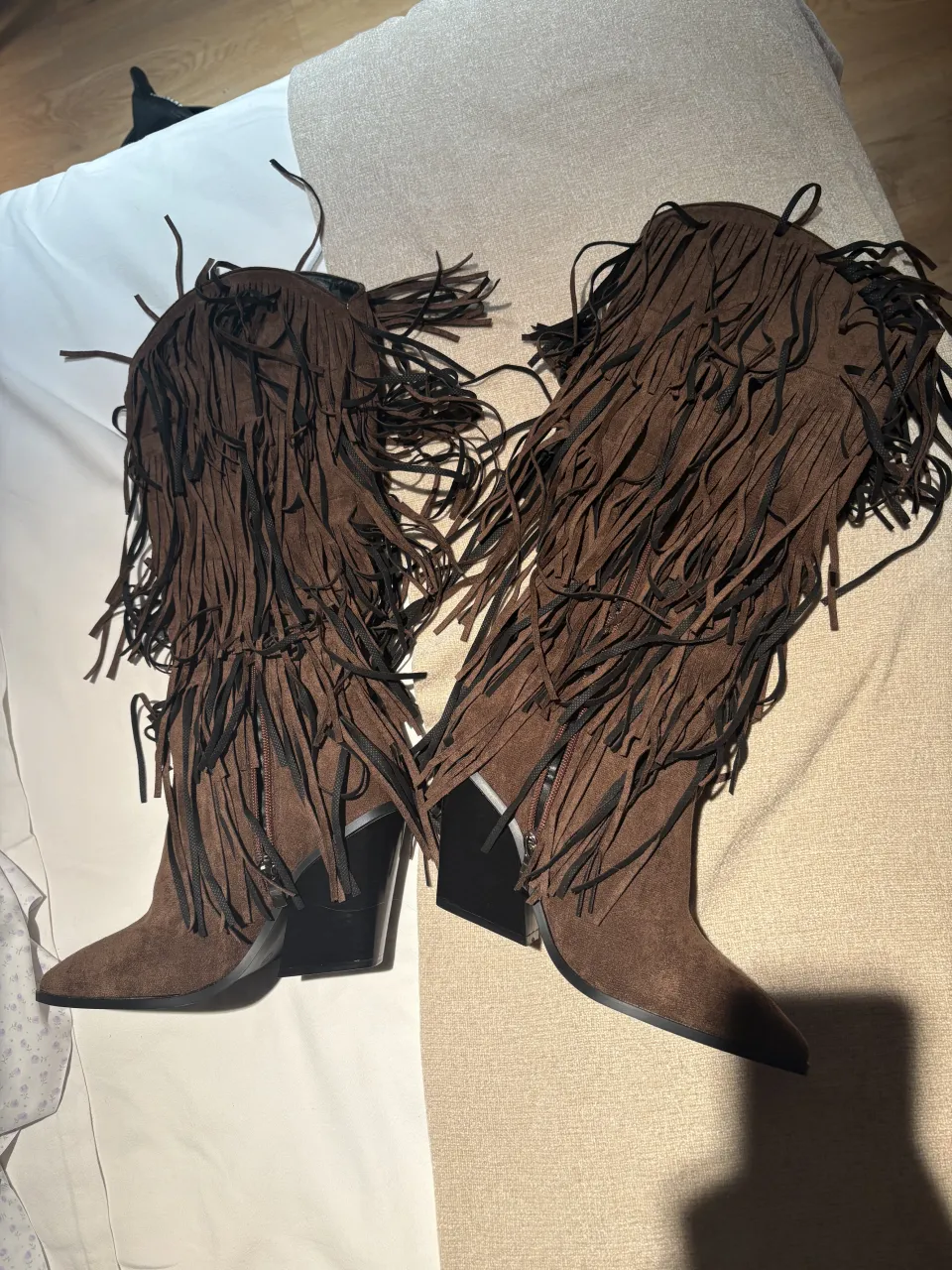 Botas marrones de caña alta con flecos largos y detalle de cierre lateral. Punta fina y taco cuadrado.