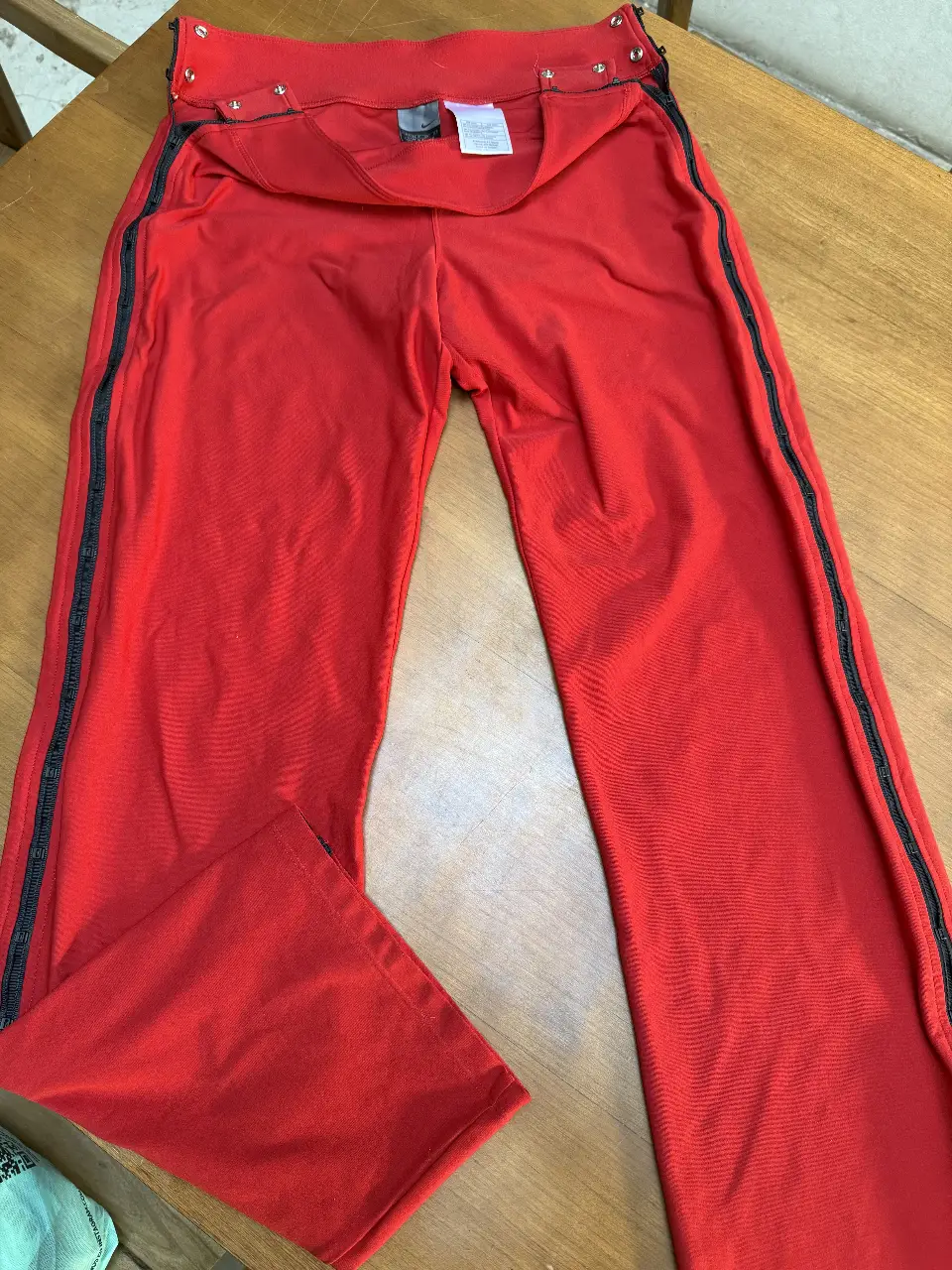 Pantalón deportivo rojo de mujer, con detalles de cierre en los laterales y logo de Nike. Ideal para actividades deportivas o un look casual. talle S