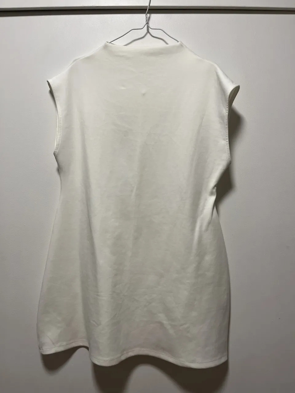 Vestido blanco sin mangas con cuello alto y botón en la espalda.