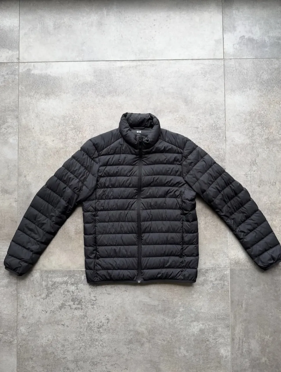 Campera negra acolchada con cierre al frente y cuello alto. Posee bolsillos laterales con cierre.