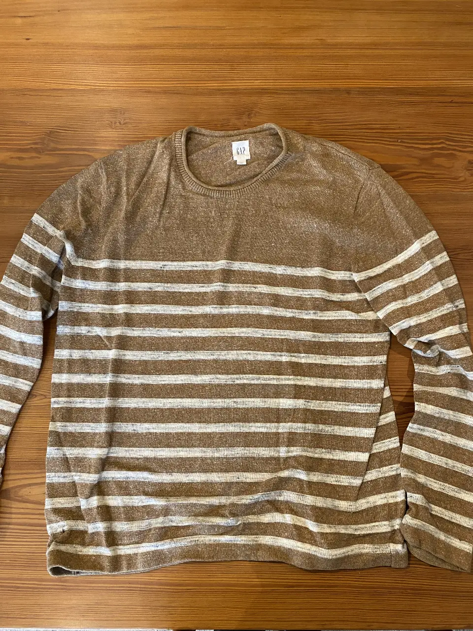 Sweater de hombre a rayas horizontales en tonos marrones y blanco. Cuello redondo y manga larga. Ideal para un look casual y cómodo.