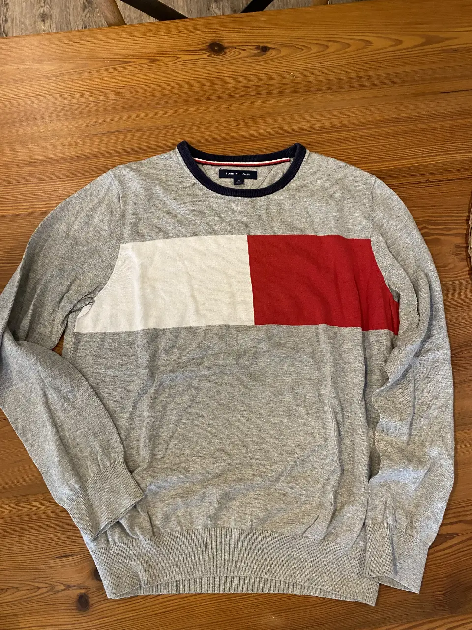 Sweater Tommy Hilfiger de hombre, de cuello redondo, con diseño a bloques en gris, blanco y rojo. Ideal para un look casual y moderno.