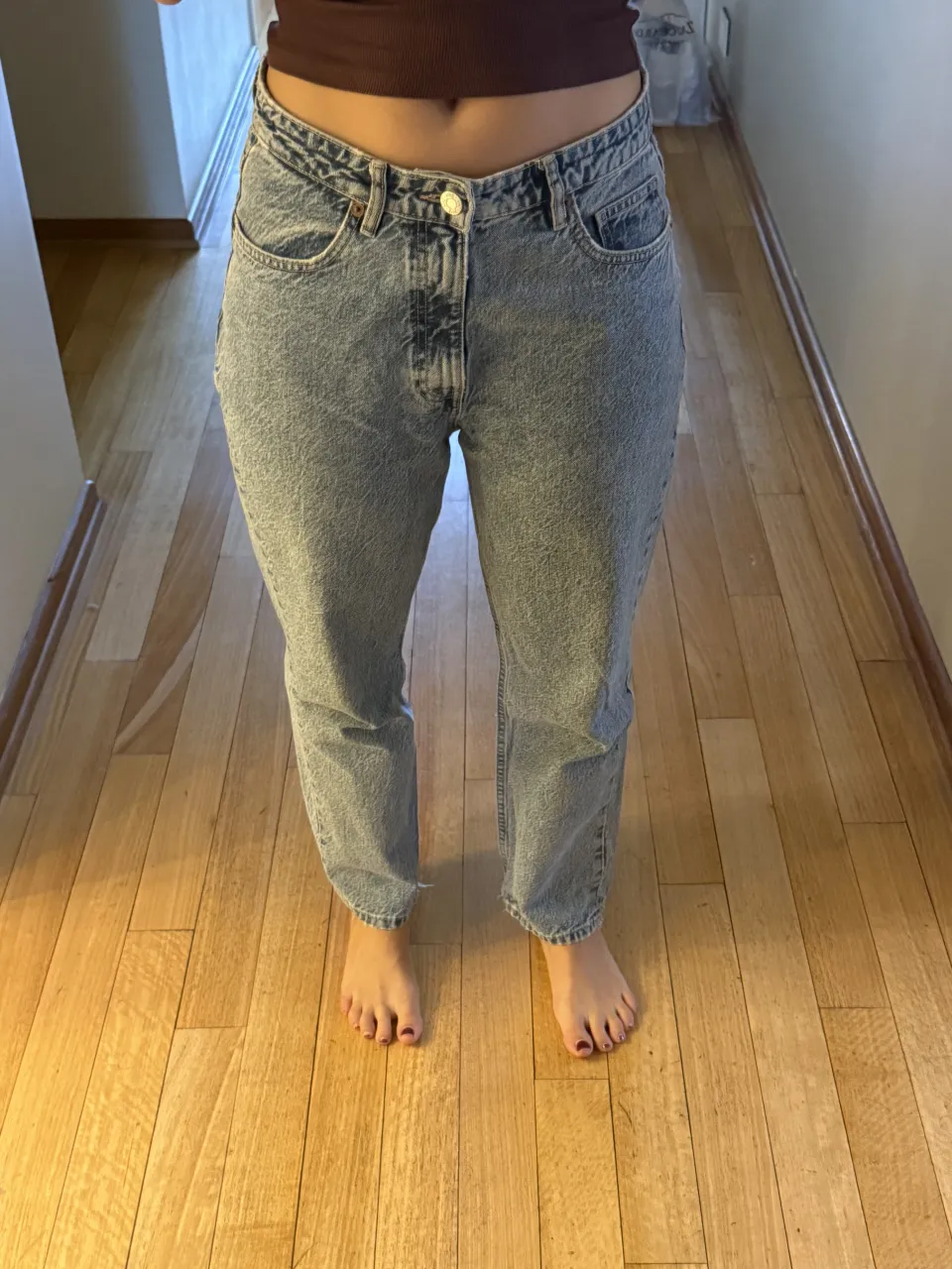 Jeans de tiro medio con lavado claro y efecto desgastado. Cierre de botón y bolsillos delanteros y traseros.