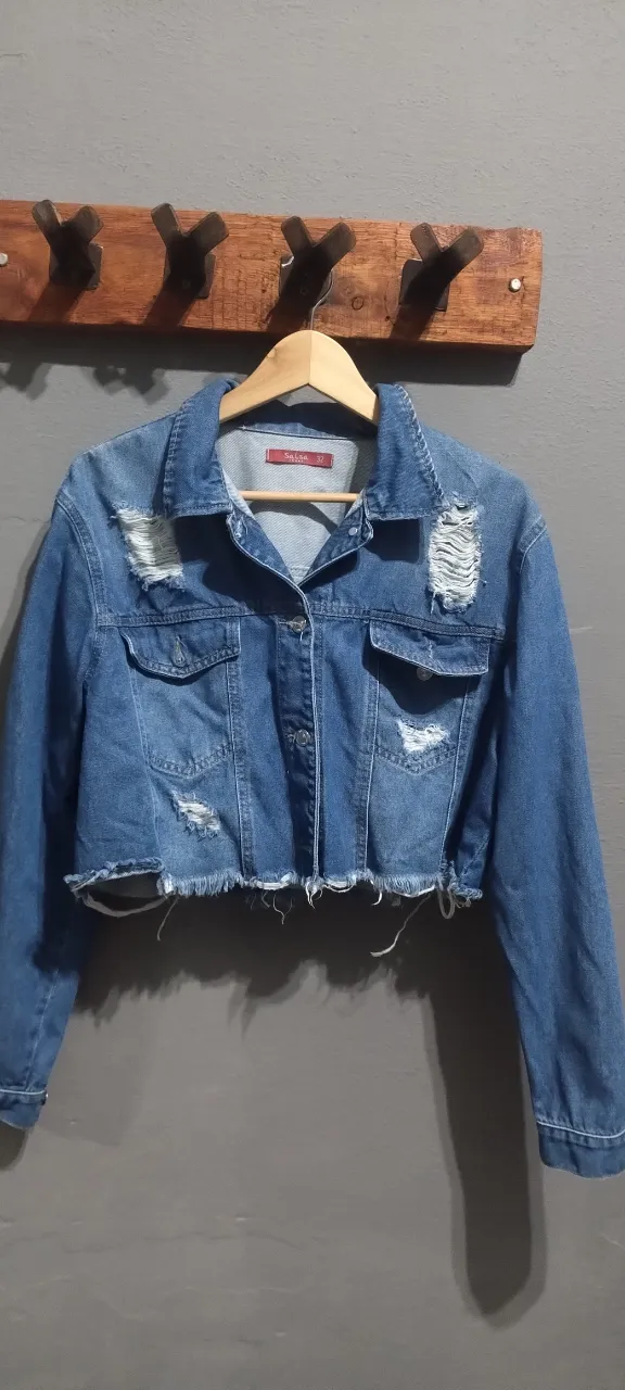 Campera de jean corta con roturas, desgastes propios de la prenda y detalles deshilachados en el borde inferior. Poco uso, muy versátil para armar looks urbanos. Posee bolsillos con solapa en el frente y botones metálicos. Talle 32.
Medidas de axila a axila: 59 cm
Largo desde cuello a ruedo: 46 cm.
