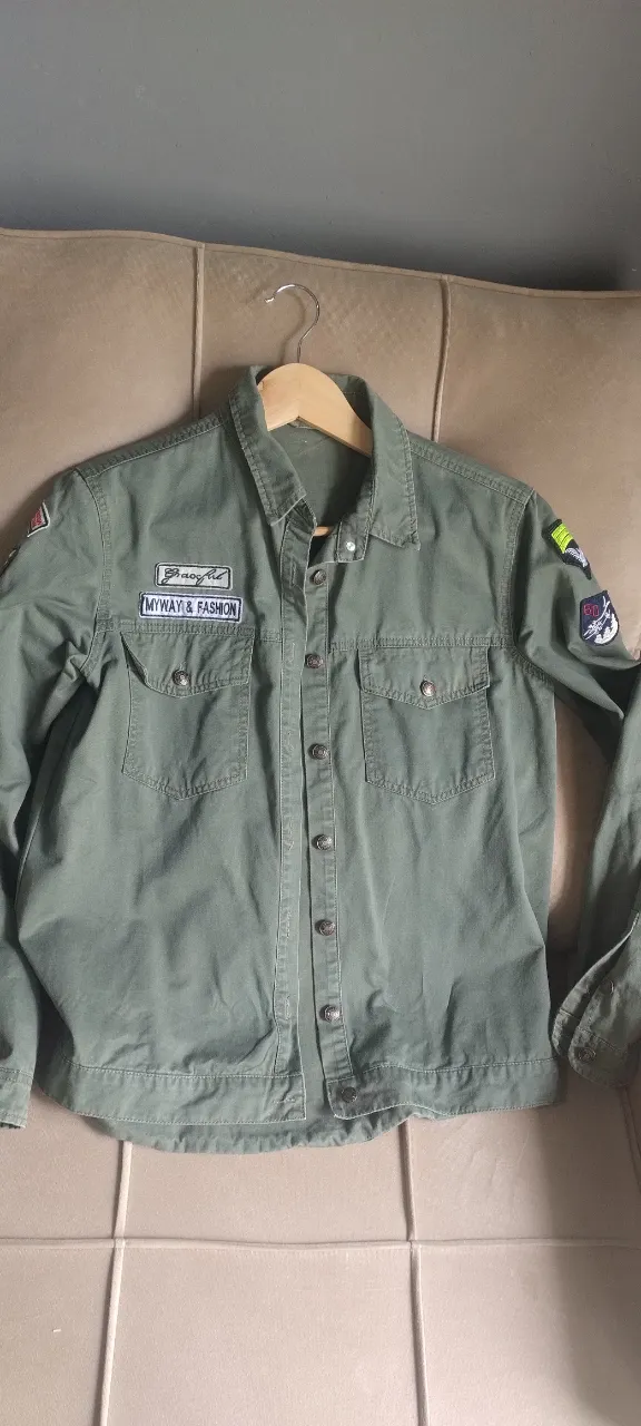 ¡Sumale onda a tus looks con esta shacket (campera-camisa) estilo militar! Es una prenda súper versátil, confeccionada en gabardina rígida color verde oliva, perfecta como media estación o para armar capas en invierno. Su diseño se destaca por una colección de parches bordados muy originales. Verde Militar. Tiene un pequeño desgaste cerca del hombro derecho, casi imperceptible.
Medidas Axila a axila: 49 cm 
Largo: 65 cm