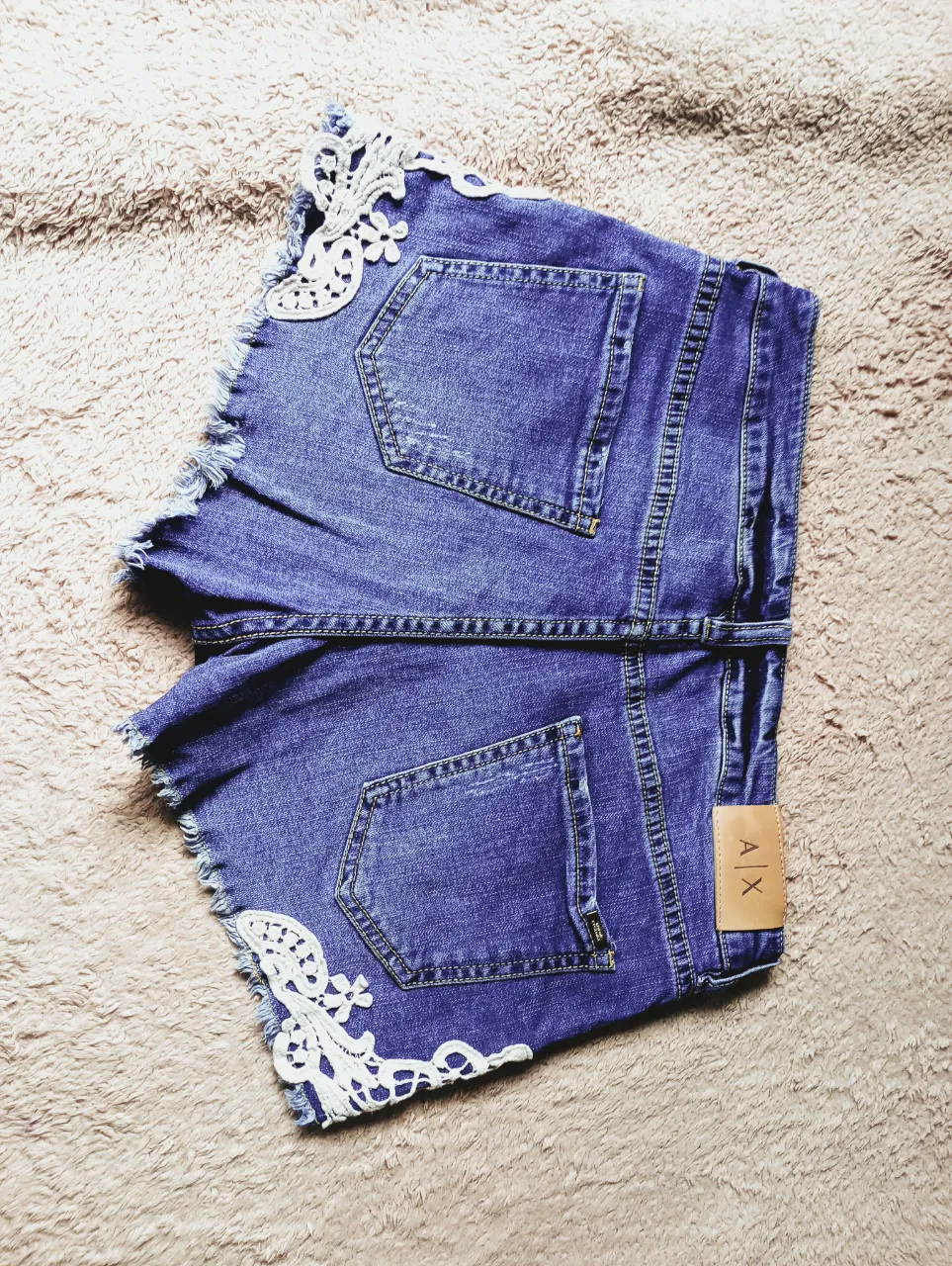 Shorts de jean azul con detalles de encaje blanco en los bordes inferiores y laterales. Poseen roturas y deshilachados en los bordes.bolsillos funcionales tanto los del fte como lo de atras. talle 38