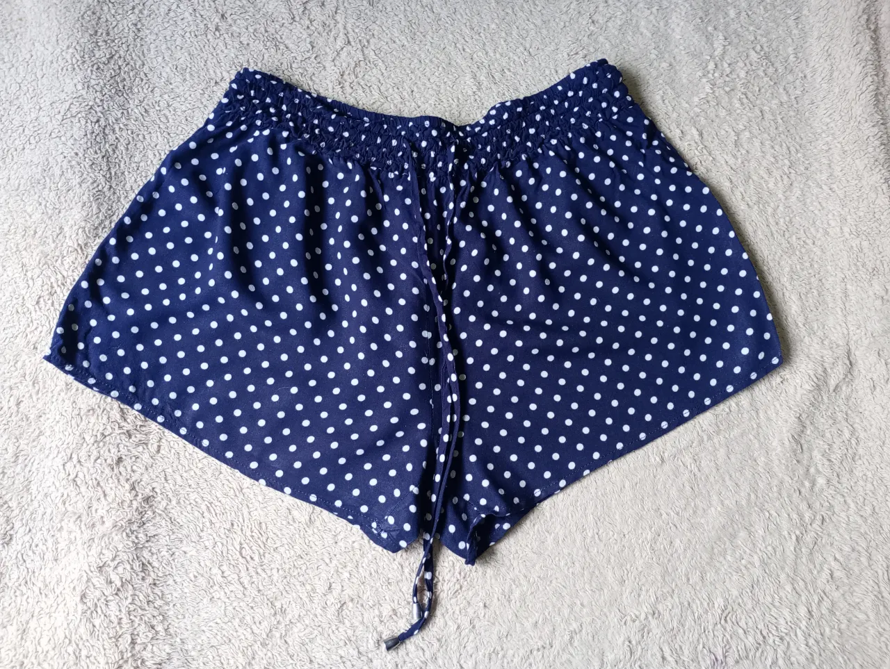 Shorts azul marino con estampa de lunares blancos. Cintura elastizada con cordón.