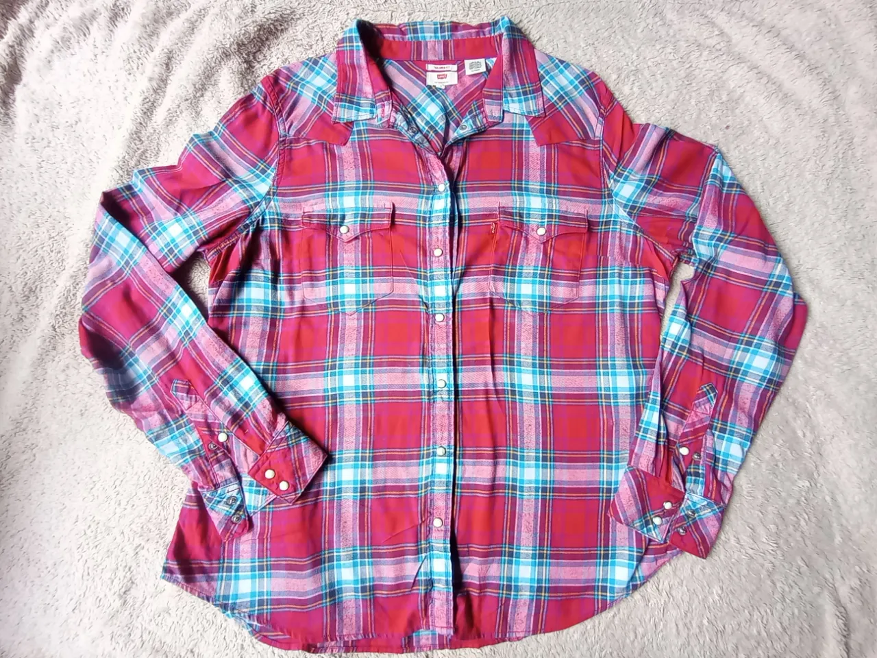 Camisa a cuadros de manga larga con botones al frente y dos bolsillos en el pecho. Los puños tienen botones.