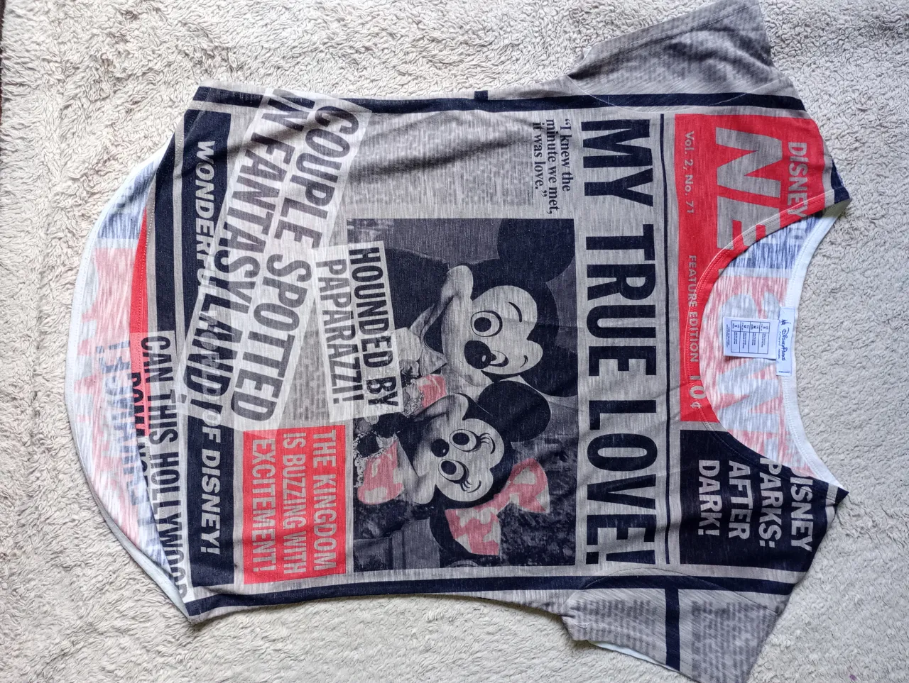 Remera gris con estampado de diario y dibujos de Mickey y Minnie Mouse. Presenta titulares como "MY TRUE LOVE" y "CAMERA SHY!".