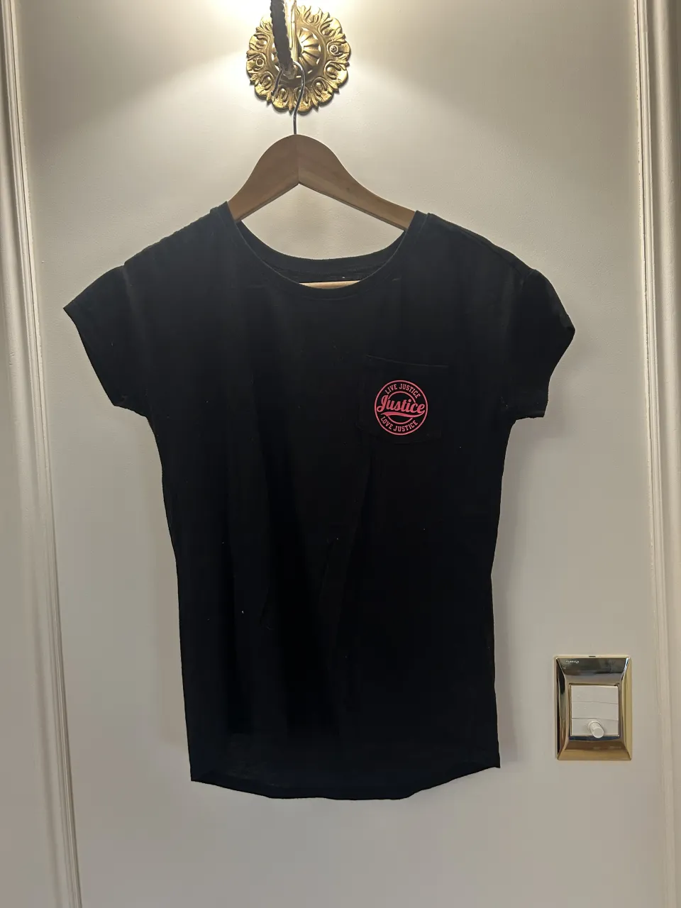 Remera negra de manga corta con estampa circular en el frente y estampa grande en la espalda con la frase "LOVE JUSTICE 2016".