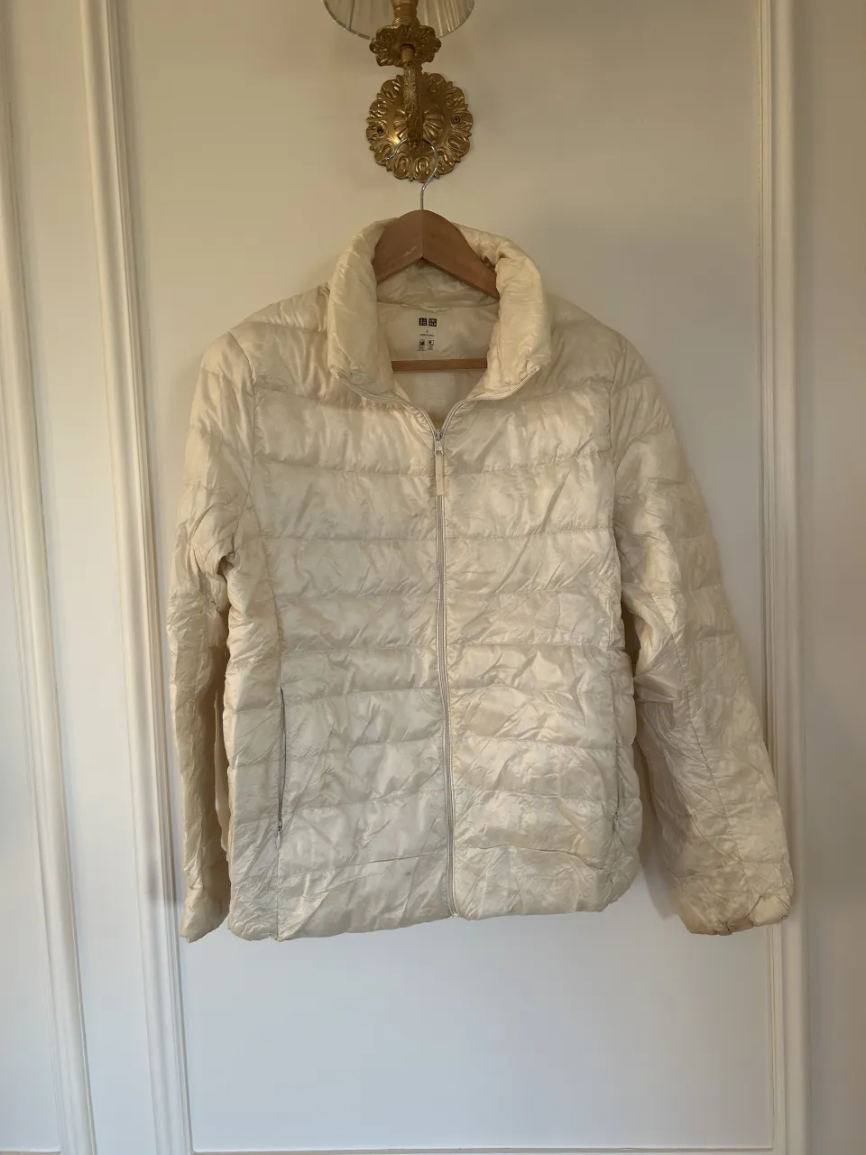 La campera más abrigada del mundo. Campera acolchada color crema, con cierre al frente y bolsillos laterales. Tiene manchas.