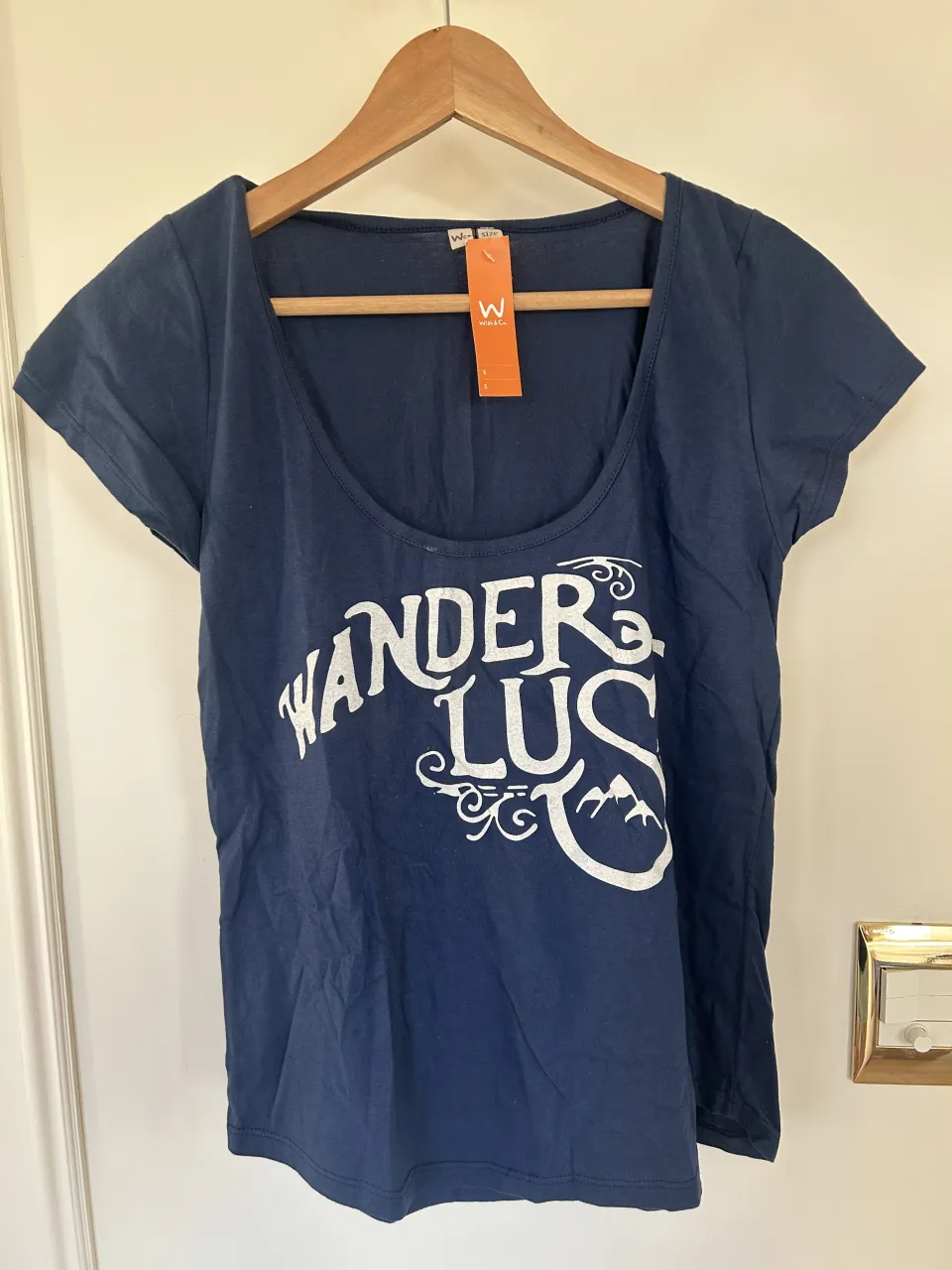Remera azul marino con estampa blanca "WANDERLUS" y un diseño de montañas.