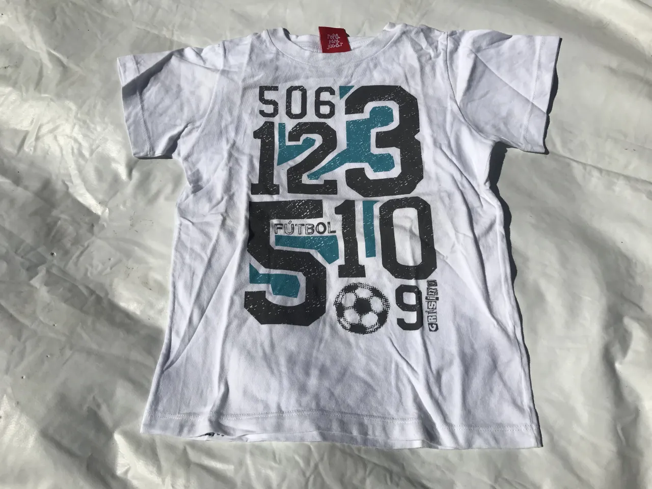 Remera blanca con estampa de números y un balón de fútbol. La estampa tiene los números 506, 123, 510, 9 y la palabra FÚTBOL.