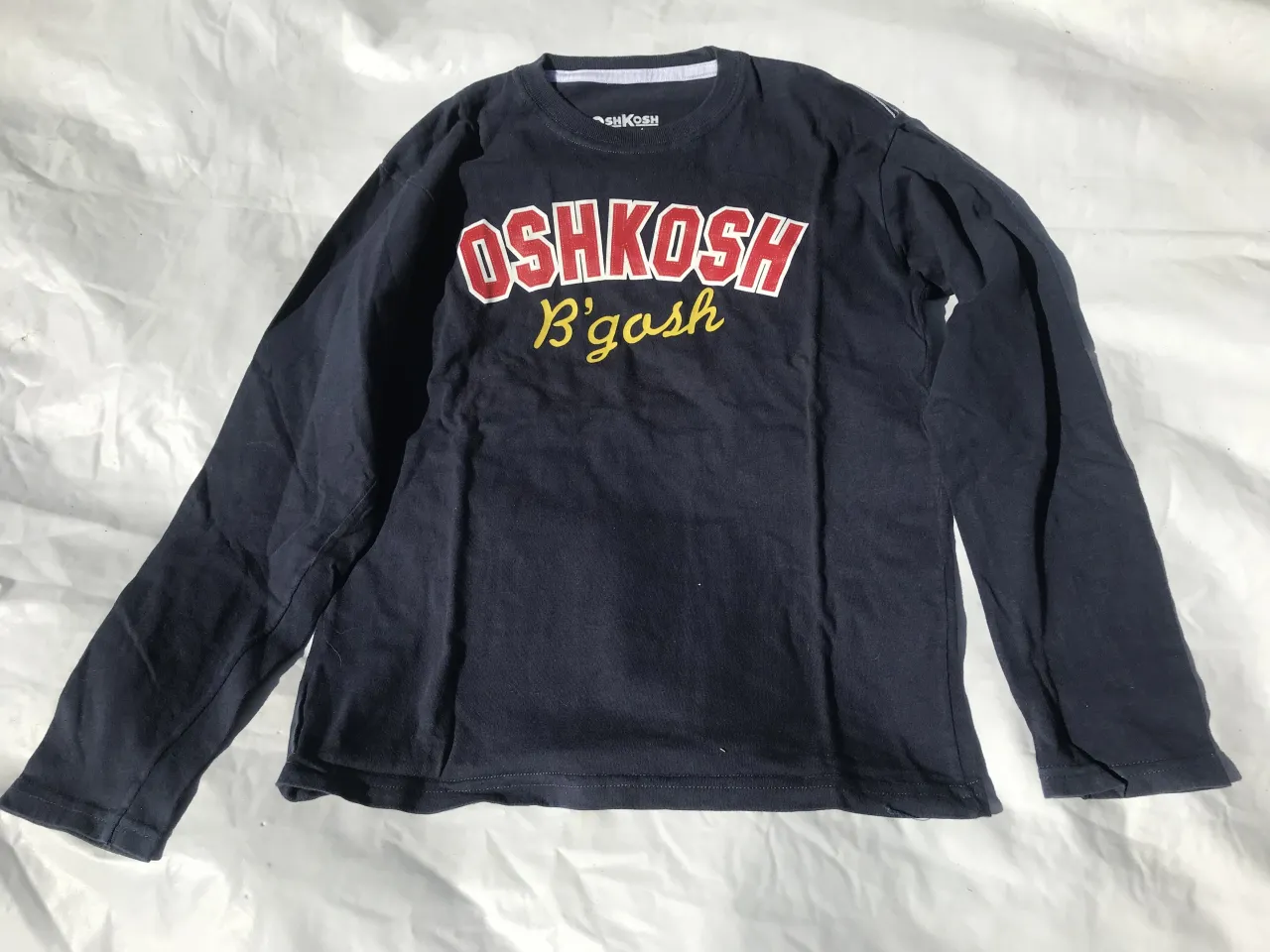 Remera azul marino de manga larga con estampa "OshKosh B'gosh" en el frente.
