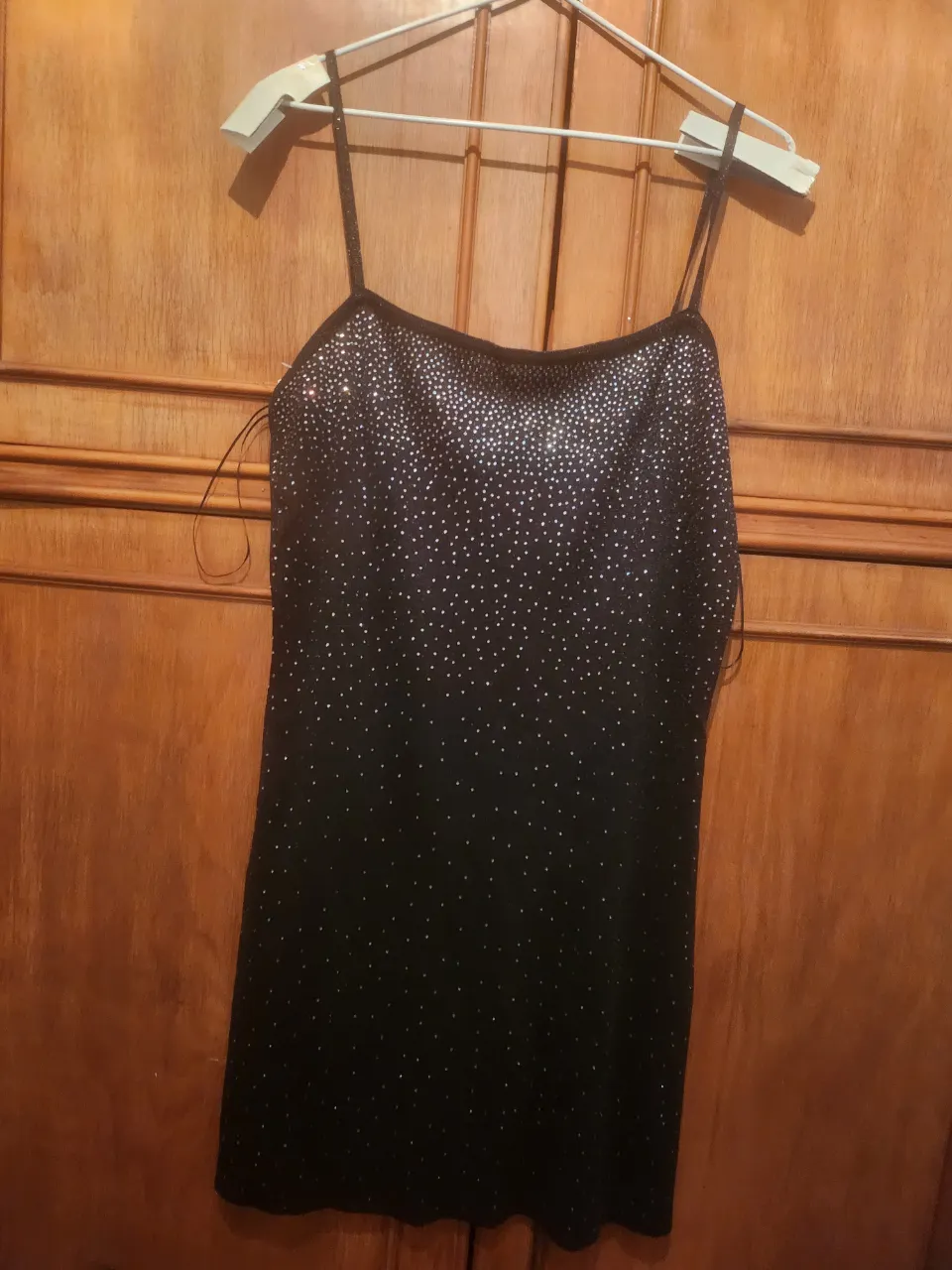 Vestido negro con tiras finas y detalles de pedrería plateada en la parte superior.