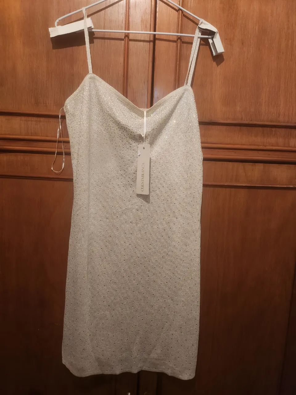 Vestido corto plateado con tiras finas. Posee brillos en toda su superficie.