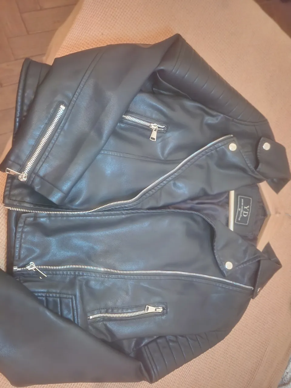 Campera de cuero sintético negra con cierre al frente y bolsillos con cierre. Tiene detalles de costuras en los hombros y puños.