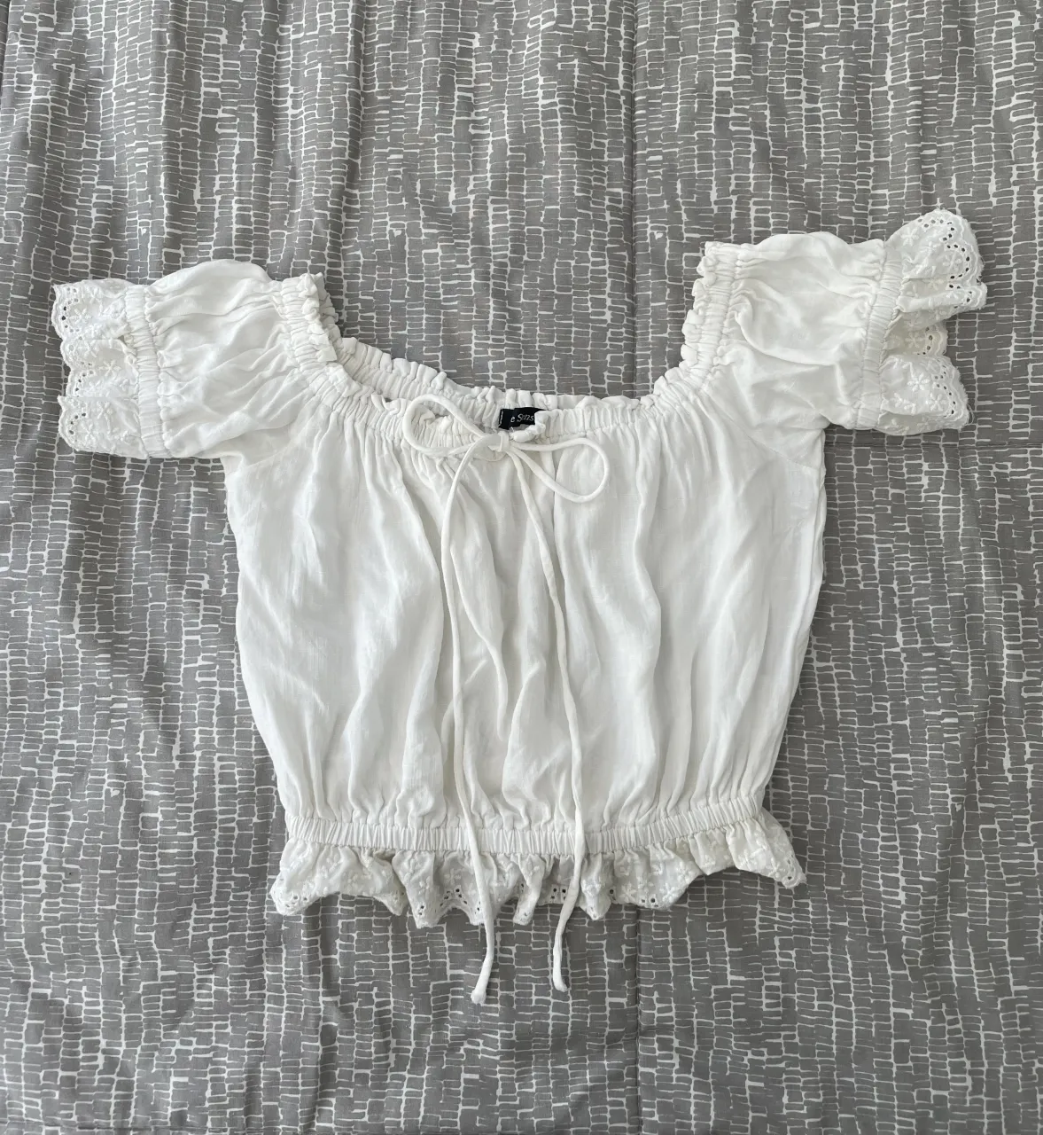 Blusa crop tipo campesina con escote off-shoulder y mangas cortas con detalles de puntilla. Tiene un moñito ajustable en el frente. Muy poco uso.