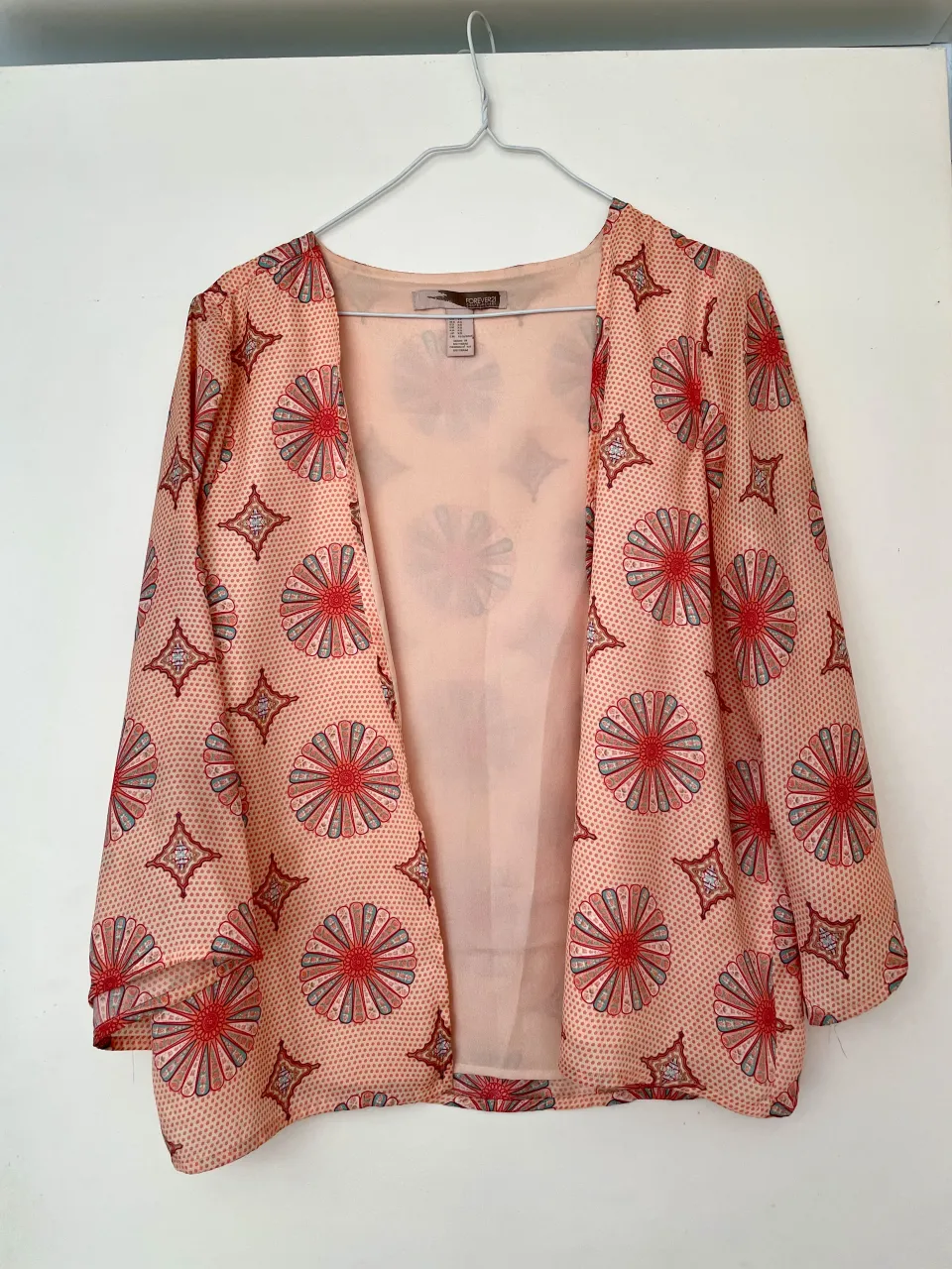 Saquito tipo Kimono súper delicado y liviano, con  estampado floral vibrante en tonos bordo, violeta, turquesa y coral  sobre una base salmón clarito. 
En la espalda tiene unas manchitas de las que no me percaté hasta verlas en la foto, son casi imperceptibles.