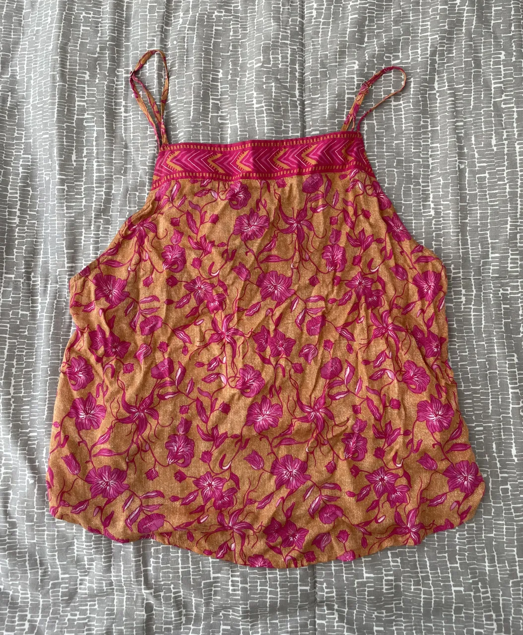 Top estampado floral playero con breteles finos y detalle de amarre en la espalda. Color ladrillo clarito y flores fucsias. Tiene unas manchitas verdes en los breteles por el mismo roce de las piezitas de metal :)