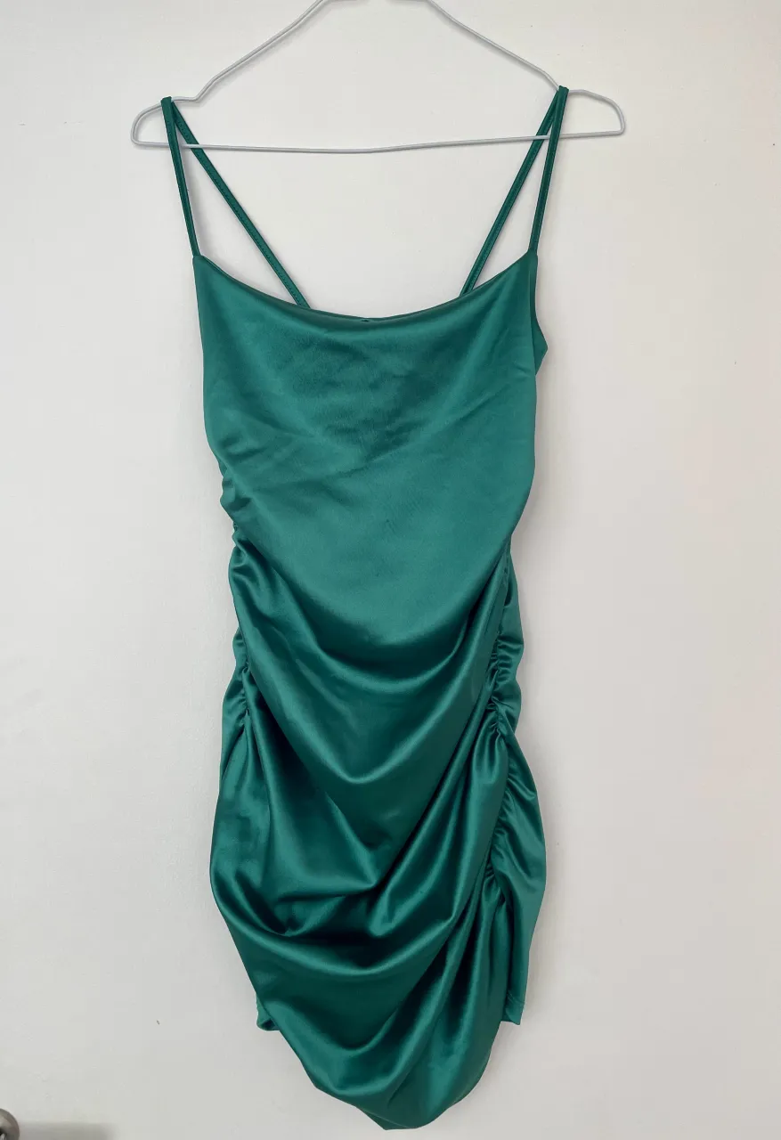 Vestido corto de satén sintético verde esmeralda, con tiras finas y detalles de fruncido en los laterales. Apenas un detalles en el frente como que se enganchó. Ideal para adolescente en epoca de cumpleaños de quince :)