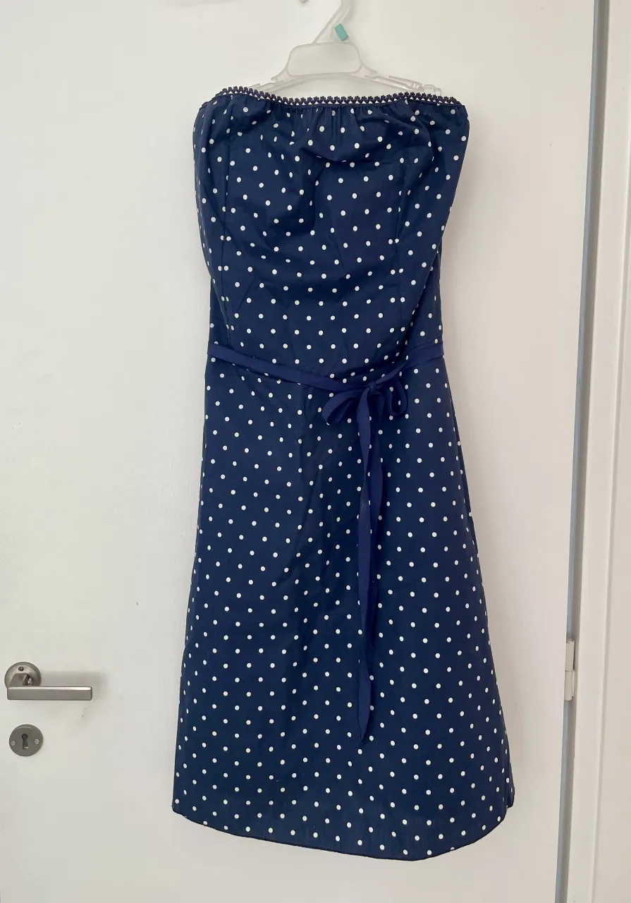 Vestido azul marino con lunares blancos, strapless con pollera evassé y  lazo a la cintura. La tela es bastante rígida, lo que hace q mantenga la forma super bien, muy bonito ;)