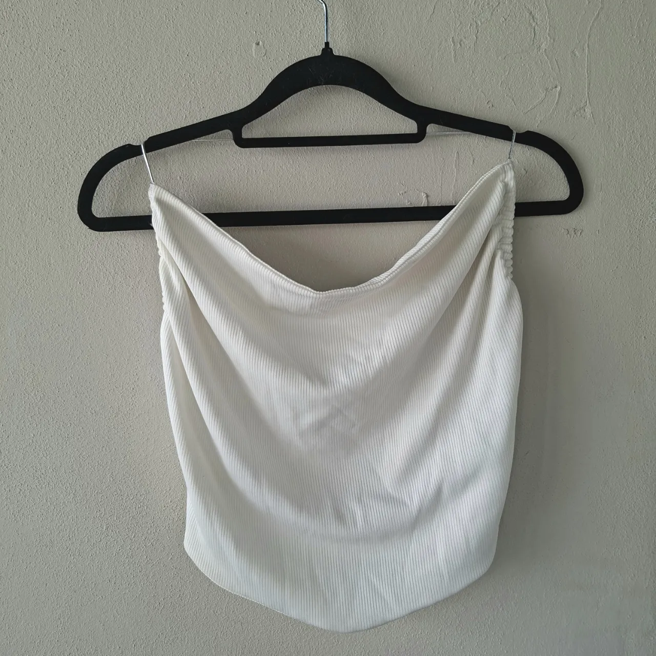 Top blanco de morley, súper canchero y moderno. Tiene un diseño drapeado en la parte delantera y tiras finas en la espalda que le dan un toque sensual. Ideal para combinar con jeans o faldas para un look de día o de noche.