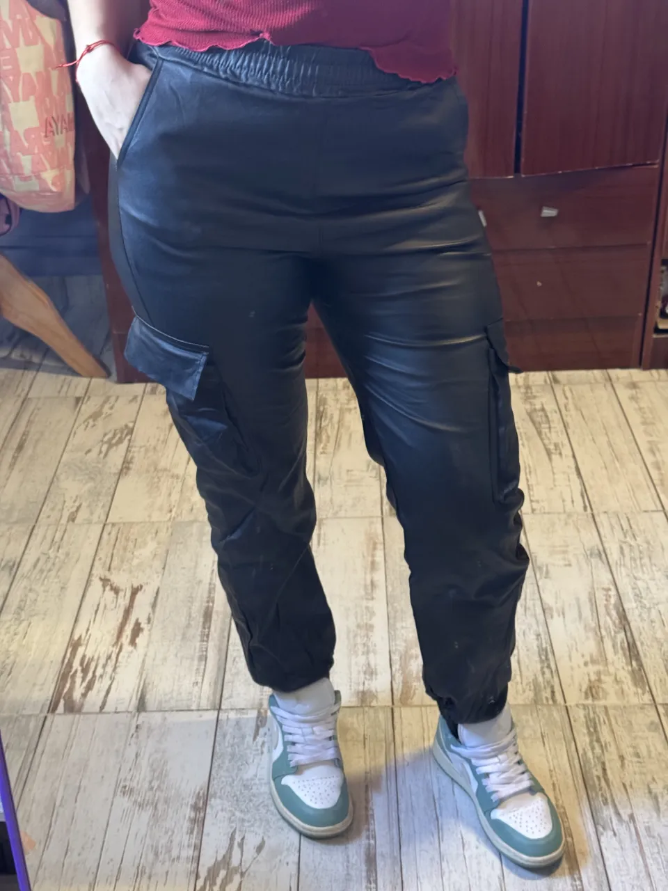 Pantalón cargo de cuero sintético negro con bolsillos laterales y cintura elastizada.
