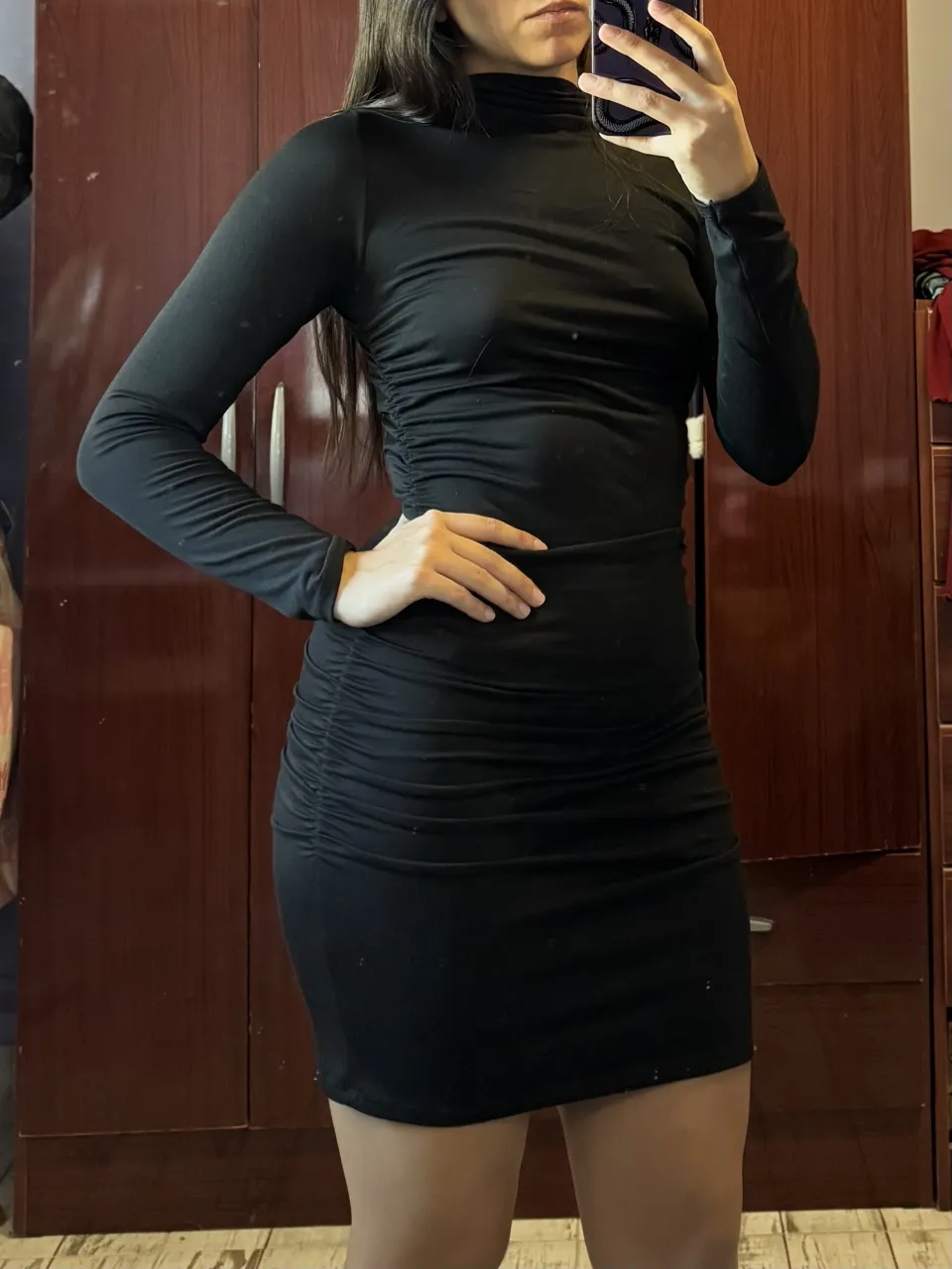 Vestido negro de manga larga con cuello alto y fruncido en los laterales y parte trasera