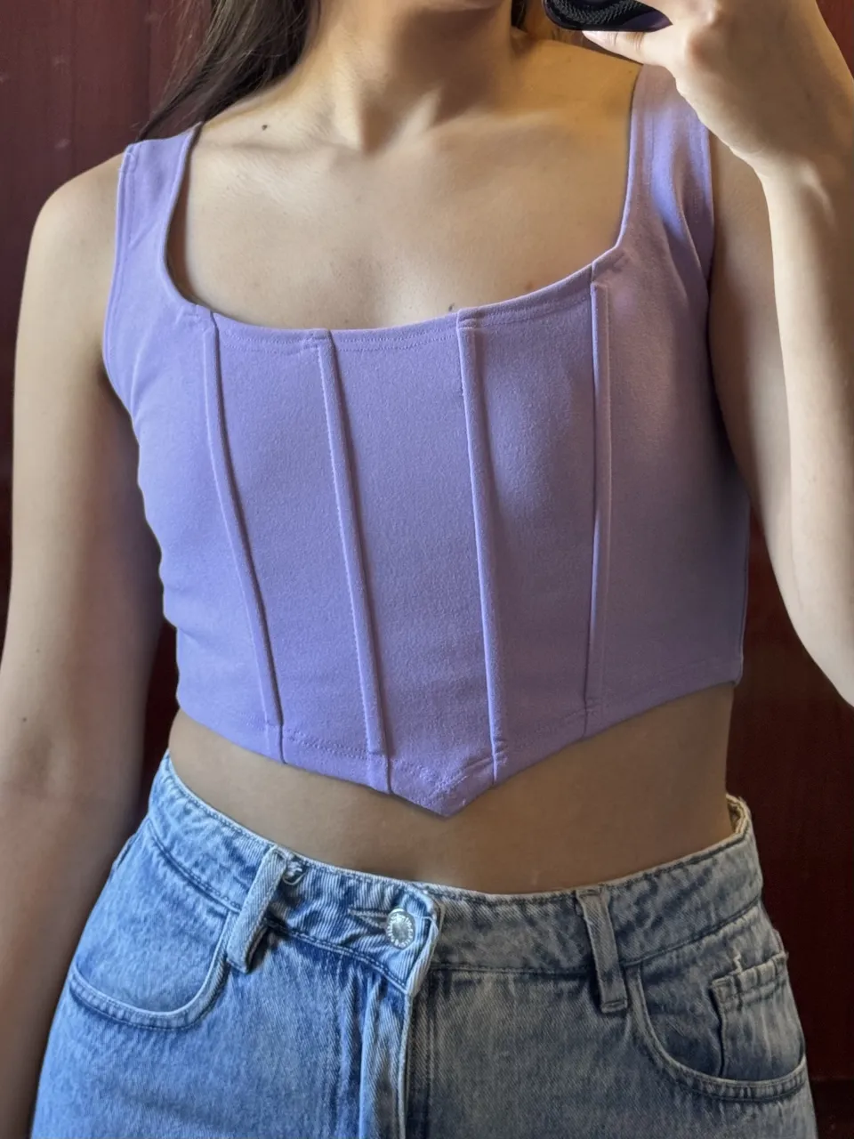 Top lila con escote cuadrado y detalles de costura verticales en el frente. Es un top corto.