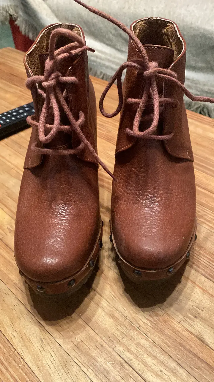 Botines de cuero marrón con cordones y taco de madera. Tienen detalles de tachas en la base y son ideales para un look casual y con estilo.