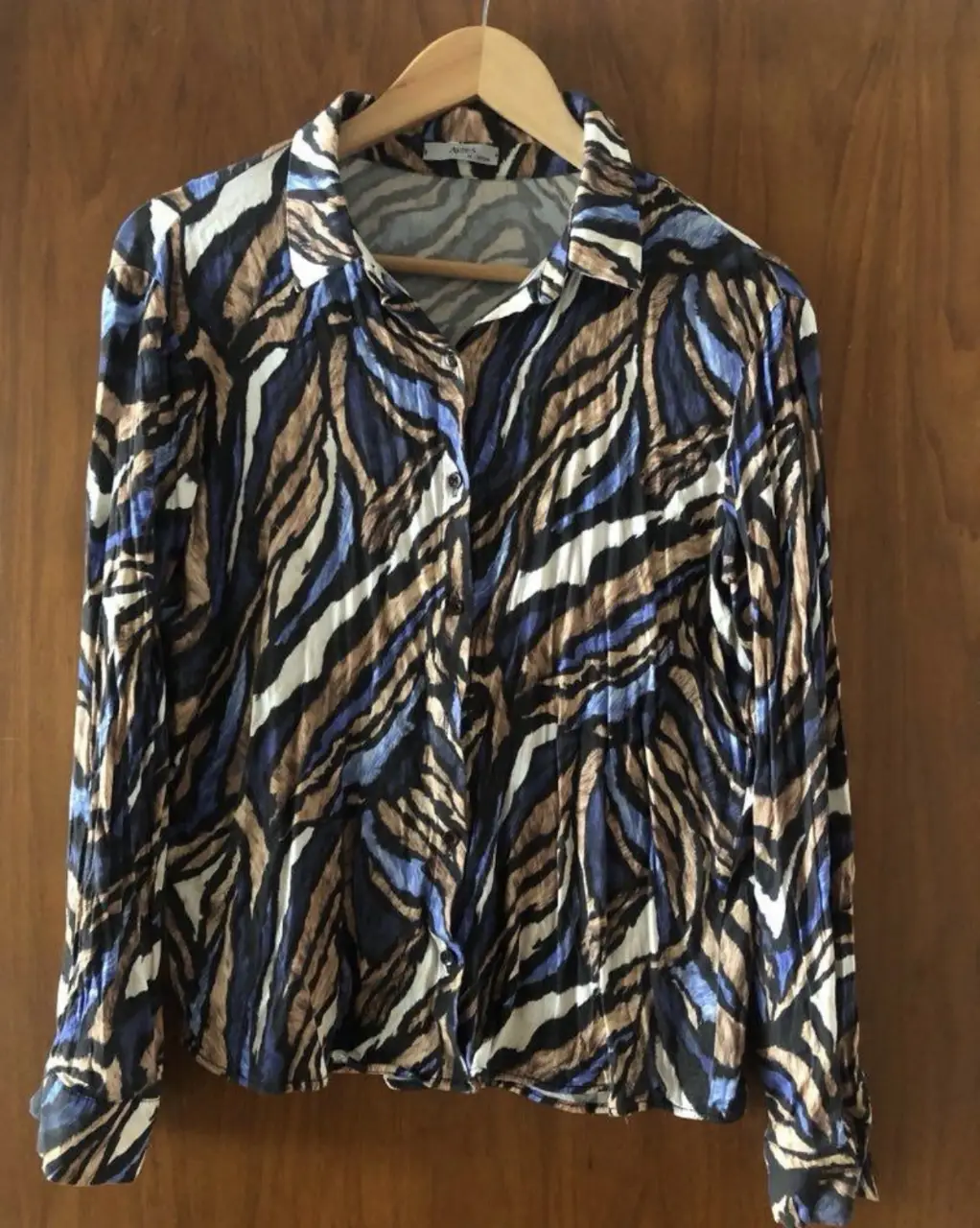 Camisa estampada con diseño de animal print en tonos azules, marrones y blancos. De manga larga, con cuello camisero y botones. talle 42 - M. le falta un botón. 