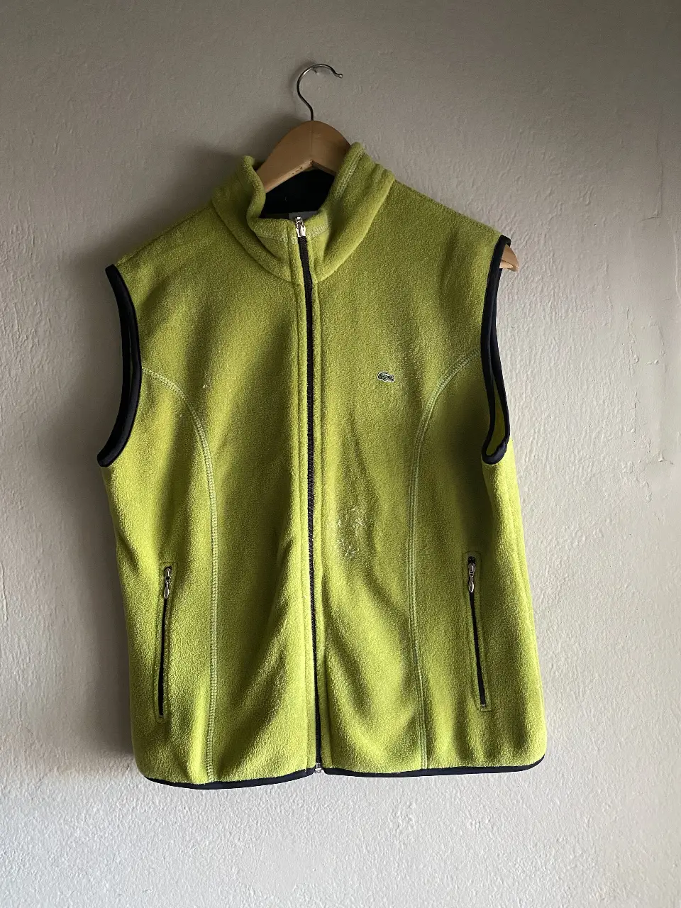 Chaleco polar Lacoste verde lima con detalles en negro. Tiene cierre completo y dos bolsillos con cierre. Ideal para usar en días frescos.