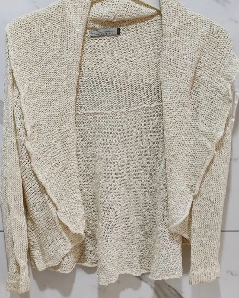 Cardigan tejido color crudo con mangas largas y cuello solapa. Posee detalles de tejido calado.