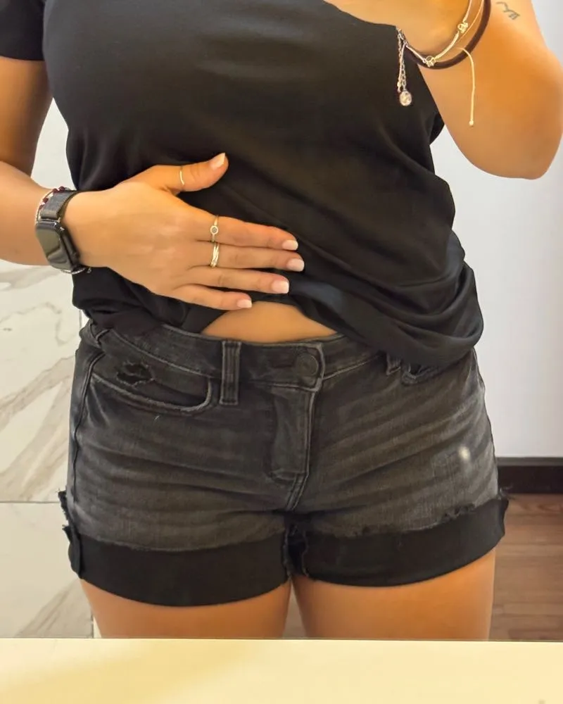 Shorts de jean negros con roturas y detalles deshilachados en los bordes. Tienen bolsillos delanteros y traseros.