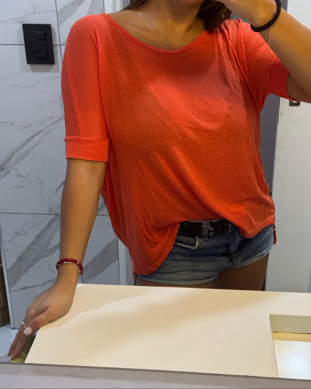 Remera de manga corta color naranja vibrante. Cuello redondo. Dobladillo en las mangas.