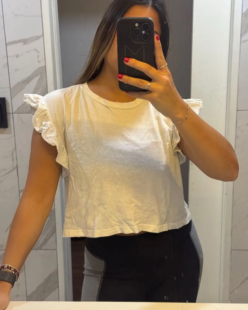 Remera blanca de algodón con mangas cortas con volados. Es un modelo crop, ideal para un look casual y moderno.