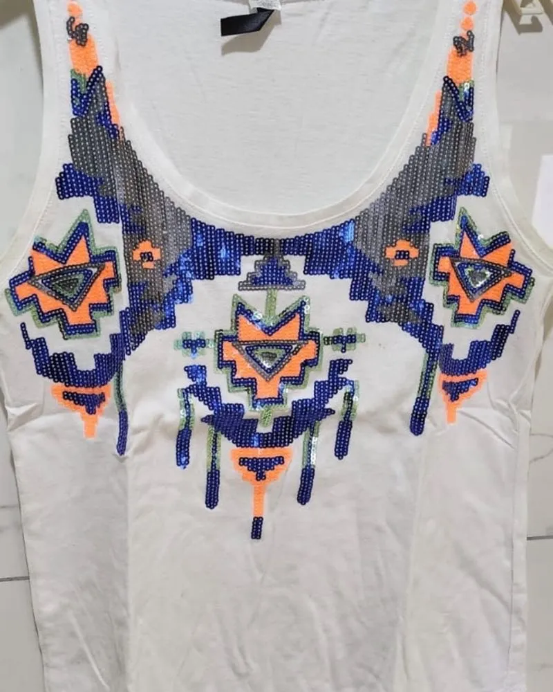 Musculosa blanca con diseño geométrico bordado con lentejuelas en la parte delantera. El diseño combina lentejuelas azules, grises, naranjas y verdes.
