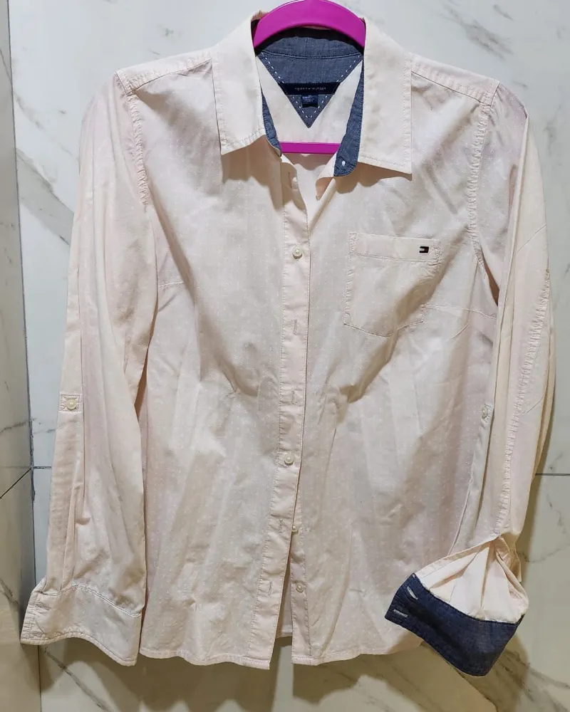 Camisa de manga larga color rosa pálido con pequeños puntos blancos. Posee cuello camisero, bolsillo en el pecho y puños con detalle de tela azul marino.